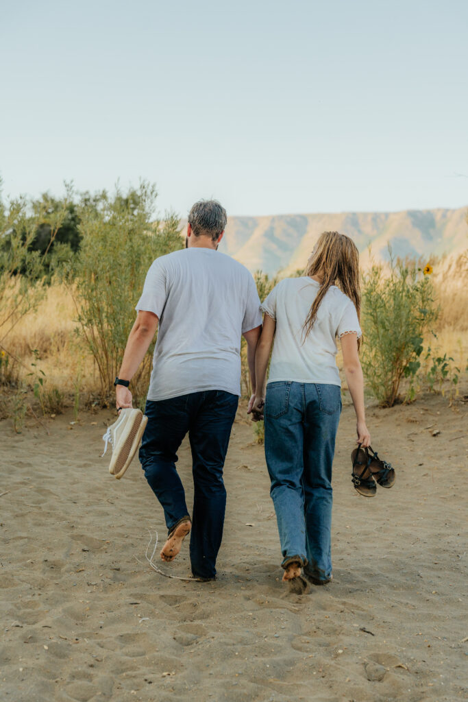 Couple walking away from the water with their shoes in-hand