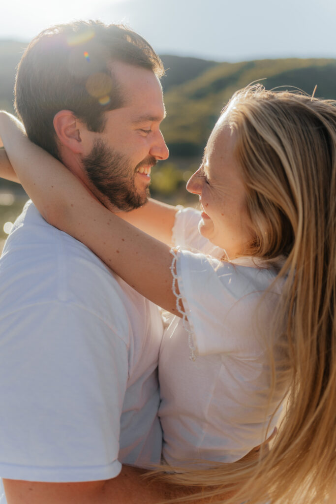 Couple hugging and smiling at each other in the sunset